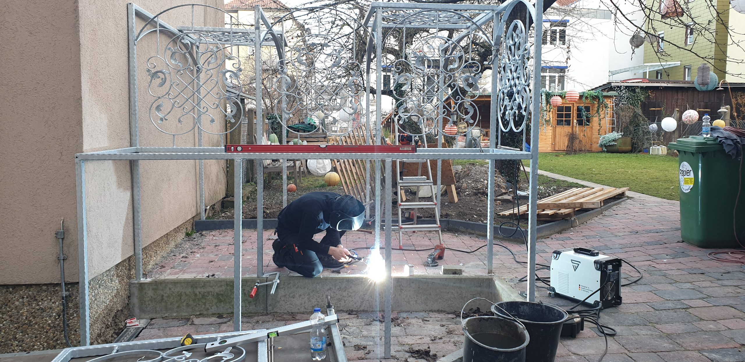 Schweißer mit Funkenflug in der Pergola-Konstruktion