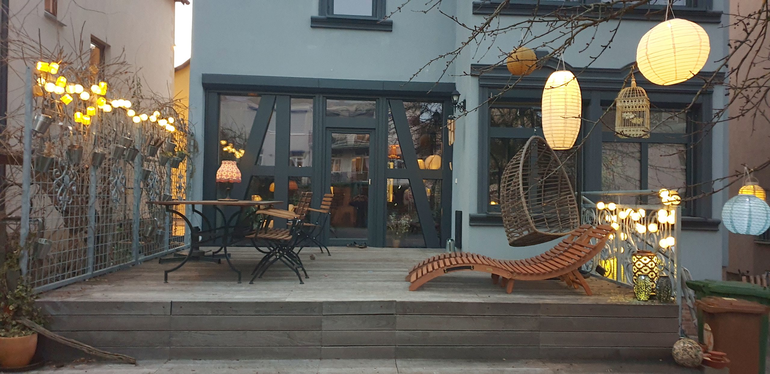 Abendterrasse mit Lichterketten und Hängesessel