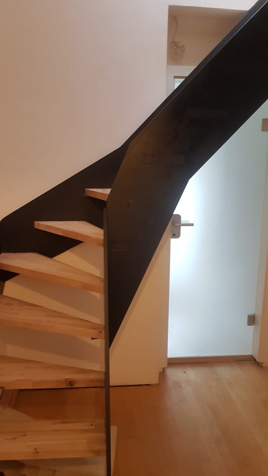 Die fertige geschwungene Treppe, schwarzer Stahl mit Holzstufen